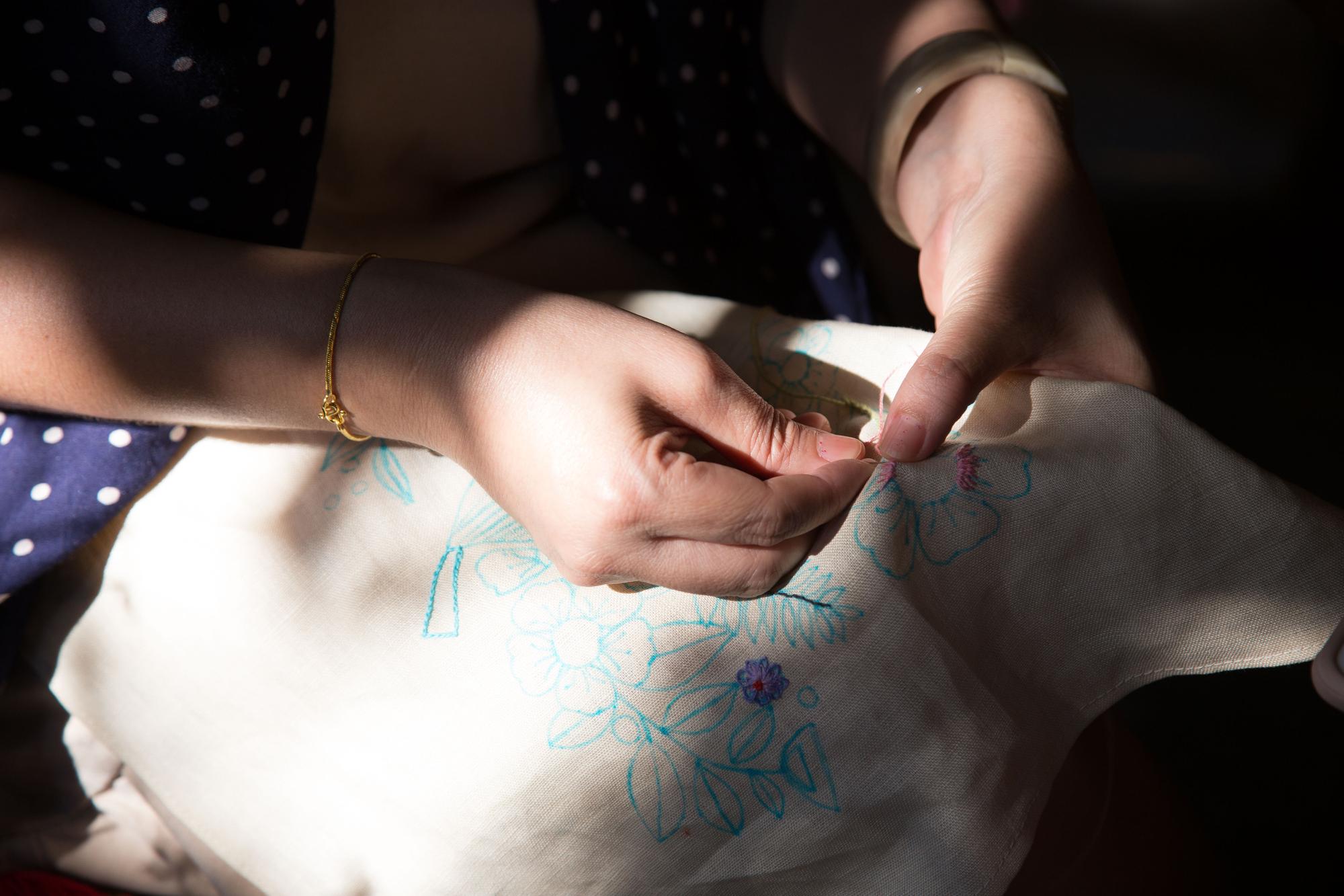 Artisan hands trimming threads on embroidered patch